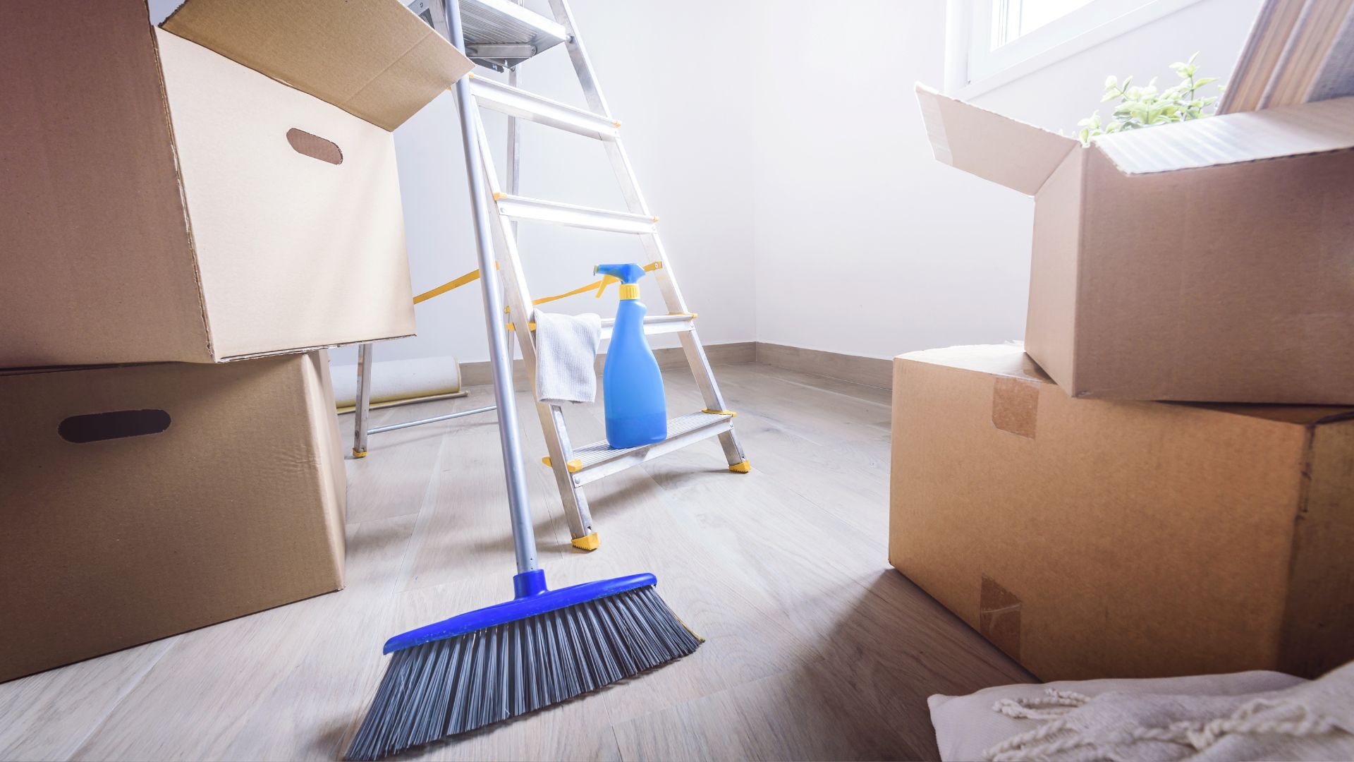 A room with boxes and a ladder with a broom