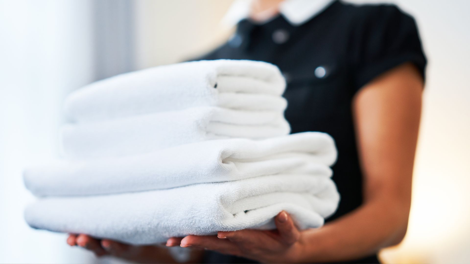 A woman holding a stack of white towels